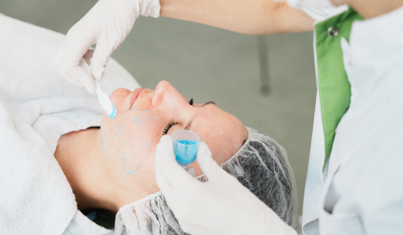 Een huidtherapeut brengt een peeling aan